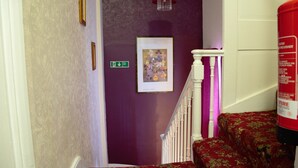 A staircase with a purple wall, a framed picture, and a fire extinguisher. - Bow Guest House (Reading)