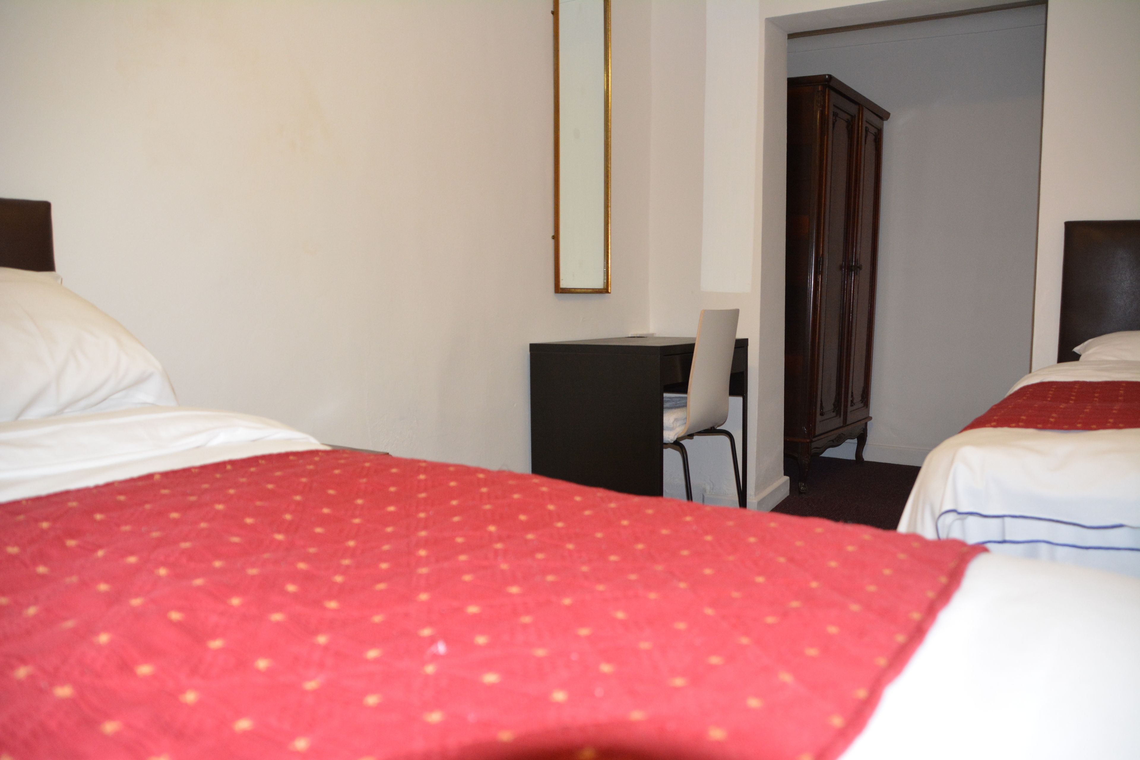 Ein Hotelzimmer mit zwei Betten, einem Schreibtisch, einem Stuhl und einem Kleiderschrank.