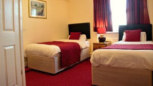 A hotel room with two beds, a nightstand, a lamp, and a window with curtains. - Bow Guest House (Reading)