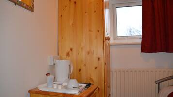 A wooden dresser with a white coffee maker, cups, and a tray.