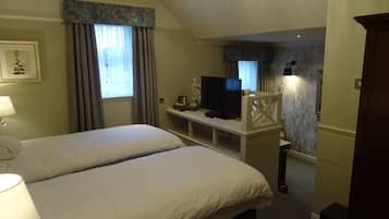A hotel room with two beds, a television on a small table, and a desk with a lamp.