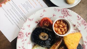 A breakfast plate with eggs, sausages, beans, and toast, a cup of coffee, and a menu.