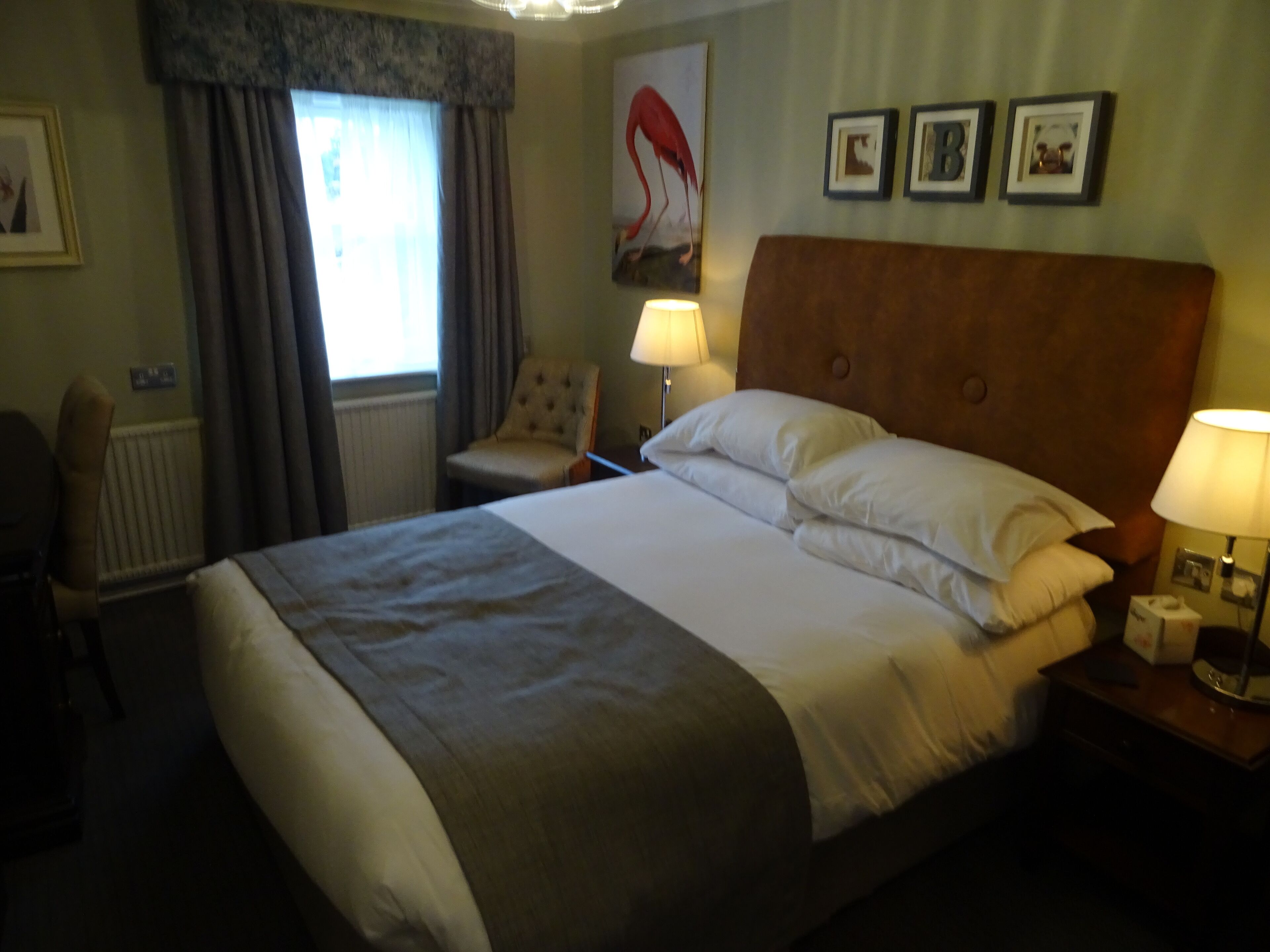 Ein Hotelzimmer mit einem großen Bett, einem Sessel, einem Schreibtisch und einer Lampe.