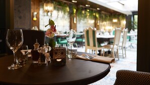 A dining table with various glassware and a candle, set in a restaurant with a view of the dining area. - Belmore (Sale)