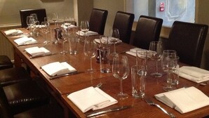 A long wooden conference table set with wine glasses, water glasses, and cutlery, surrounded by dark leather chairs. - Bell House Hotel & Restaurant (Chippenham)