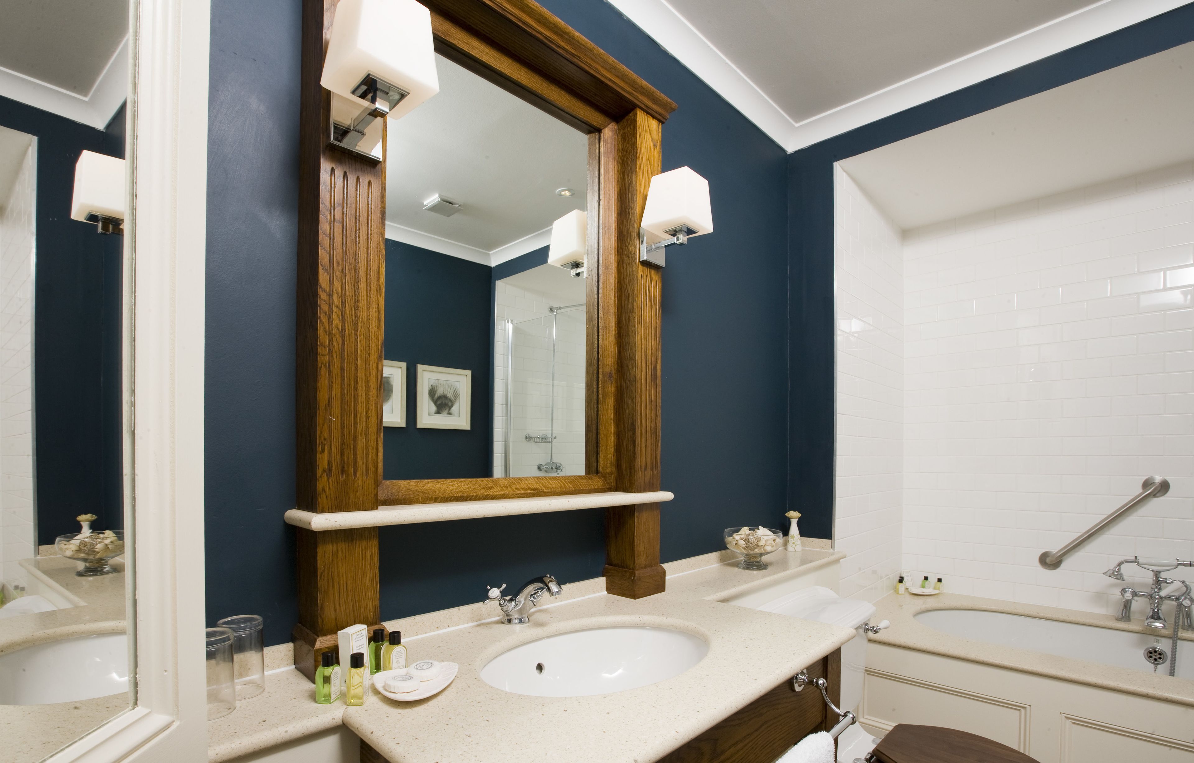 Une salle de bain avec un grand miroir, deux lavabos et une baignoire.