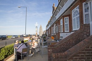 A seaside hotel with outdoor seating, a prominent anchor sculpture, and a view of the sea. - Marine Hotel (Whitstable)
