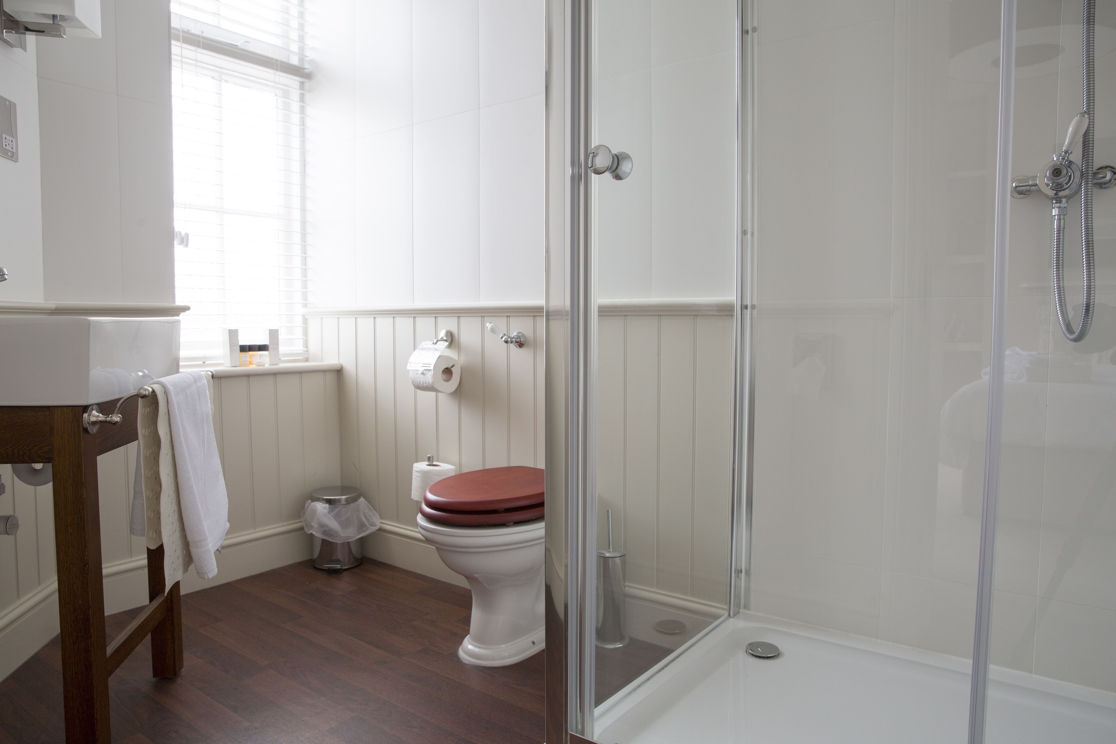 Een badkamer met toilet, douchecabine en houten wastafelmeubel met een handdoek.
