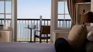 A hotel room with a balcony, a table with a cup and saucer, and a chair. - Marine Hotel (Whitstable)