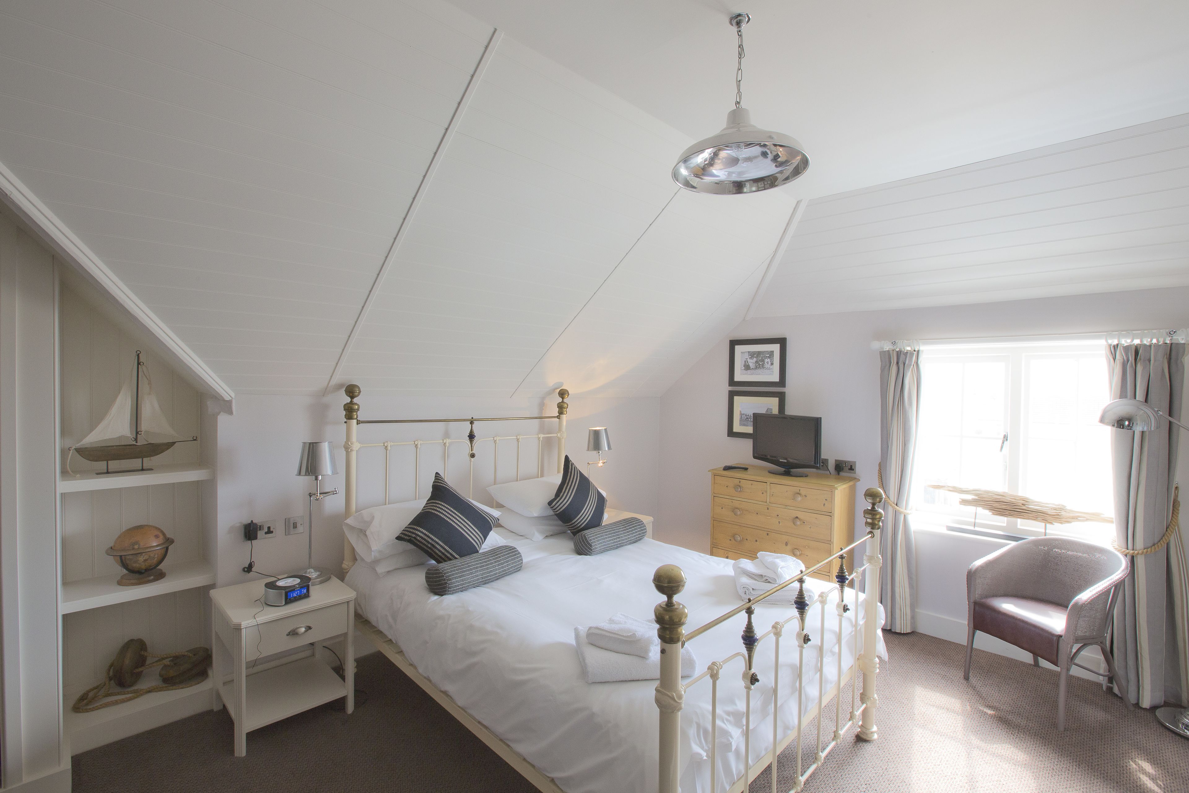 A neatly arranged bedroom with a bed, bedside table, lamp, and a chair.