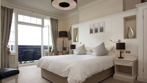 A spacious bedroom with a large bed, a nightstand, a lamp, and a view of the balcony. - Marine Hotel (Whitstable)