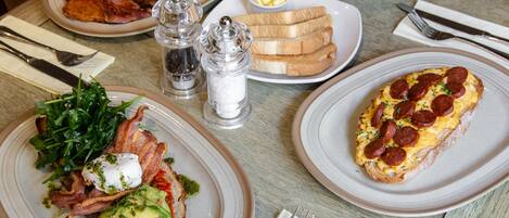 A table set with various breakfast dishes including toast, eggs, and a salad.