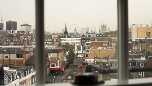 A cityscape through a window with buildings, a street, and a distant Ferris wheel. - St. George' s Inn Victoria (London)