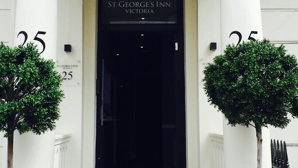 The entrance of St. George's Inn, Victoria, with a black door and white columns. - St. George' s Inn Victoria (London)