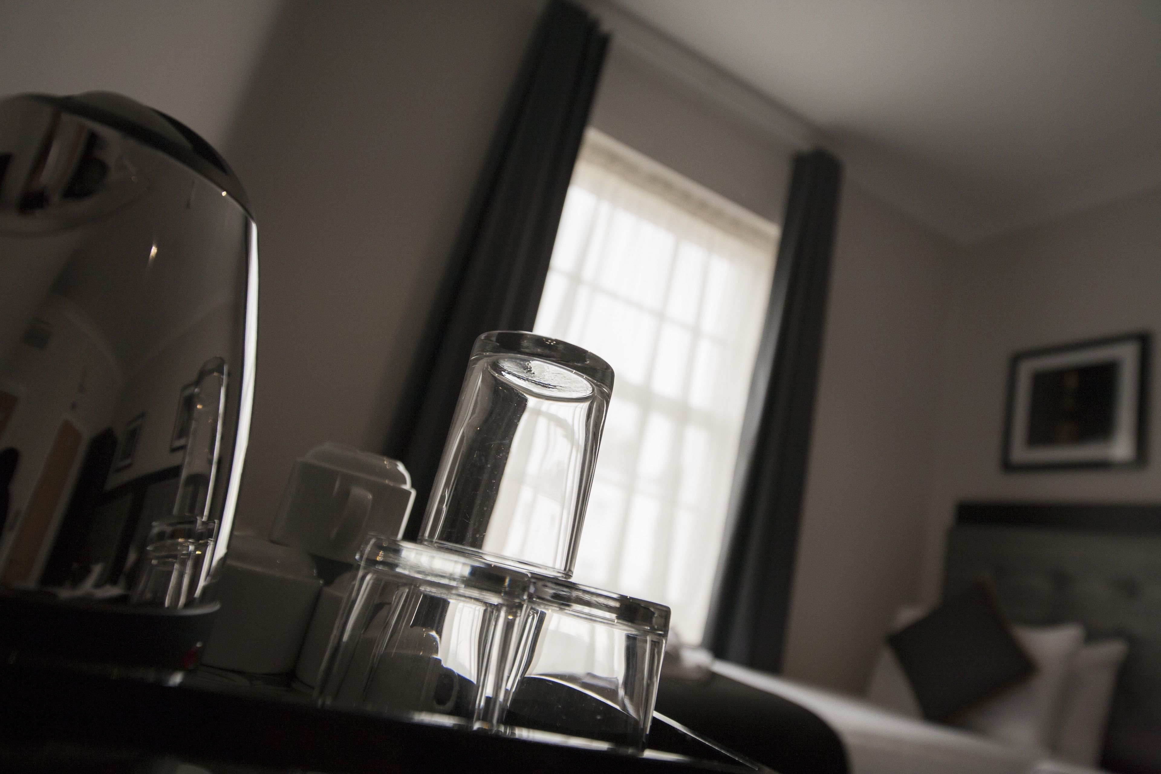 Una habitación de hotel con una cama, una cafetera y un ventanal con cortinas.