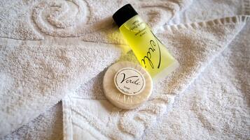 A bottle of olive oil, a bar of soap, and a towel with a floral pattern.