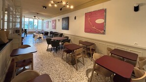Un comedor amplio con varias mesas y sillas, una lámpara decorativa en el techo y obras de arte en las paredes.