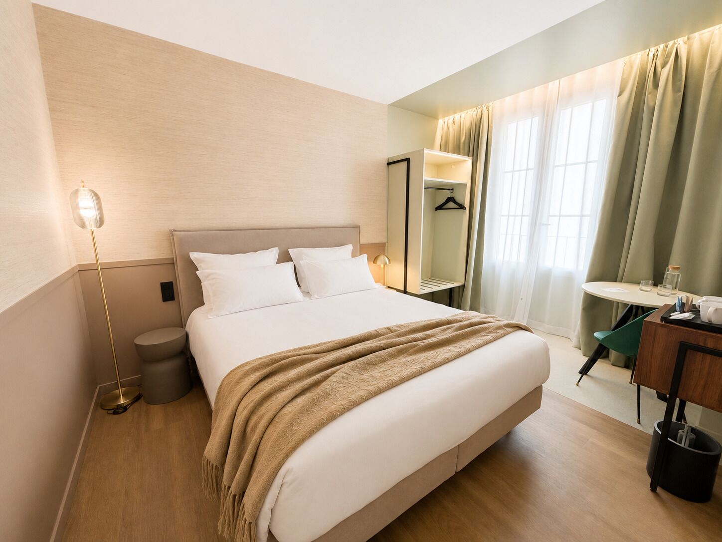 Une chambre d’hôtel équipée d’un lit, d’une table de chevet, d’une lampe et offrant une vue sur l’extérieur par une fenêtre.