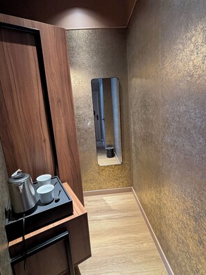 Ein modernes Badezimmer mit einem Holzwaschtisch, einem Spiegel und einer Ablage mit Wasserkocher und Tassen.