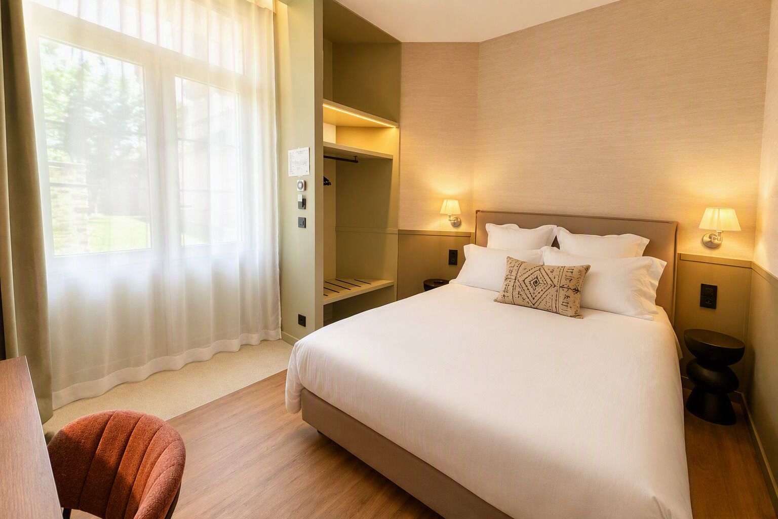 Habitación de hotel con una cama grande, dos lámparas de noche, un escritorio y una silla.