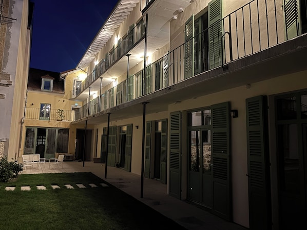 Un hotel de varios pisos con balcones, un patio interior y una fachada bien iluminada.