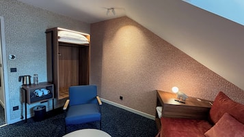 Een hotelkamer met een bed, bureau, stoel, klein tafeltje, kast en lamp.