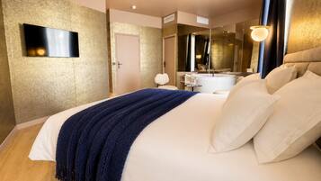 A hotel room with a large bed, a flat-screen TV, a bathroom with a bathtub, and a mirror.