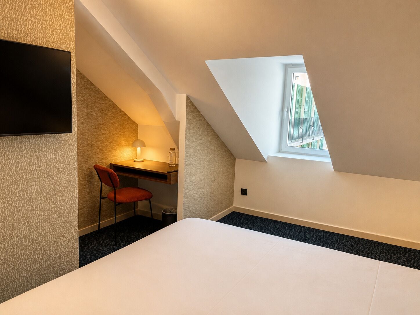 Une chambre à coucher avec un lit, un bureau, une chaise, une lampe et une fenêtre.