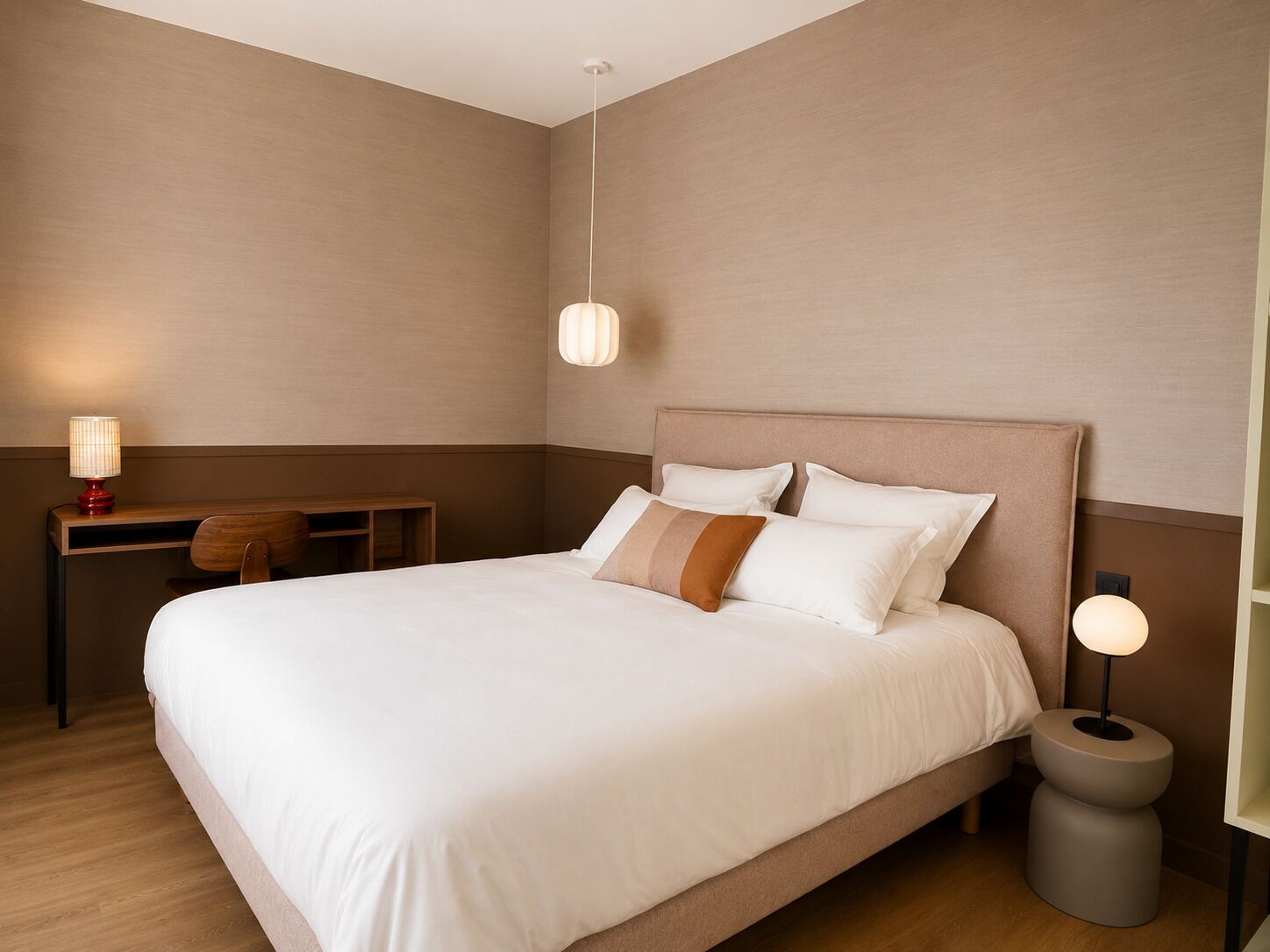 A hotel room with a large bed, bedside lamps, a desk, and a chair.