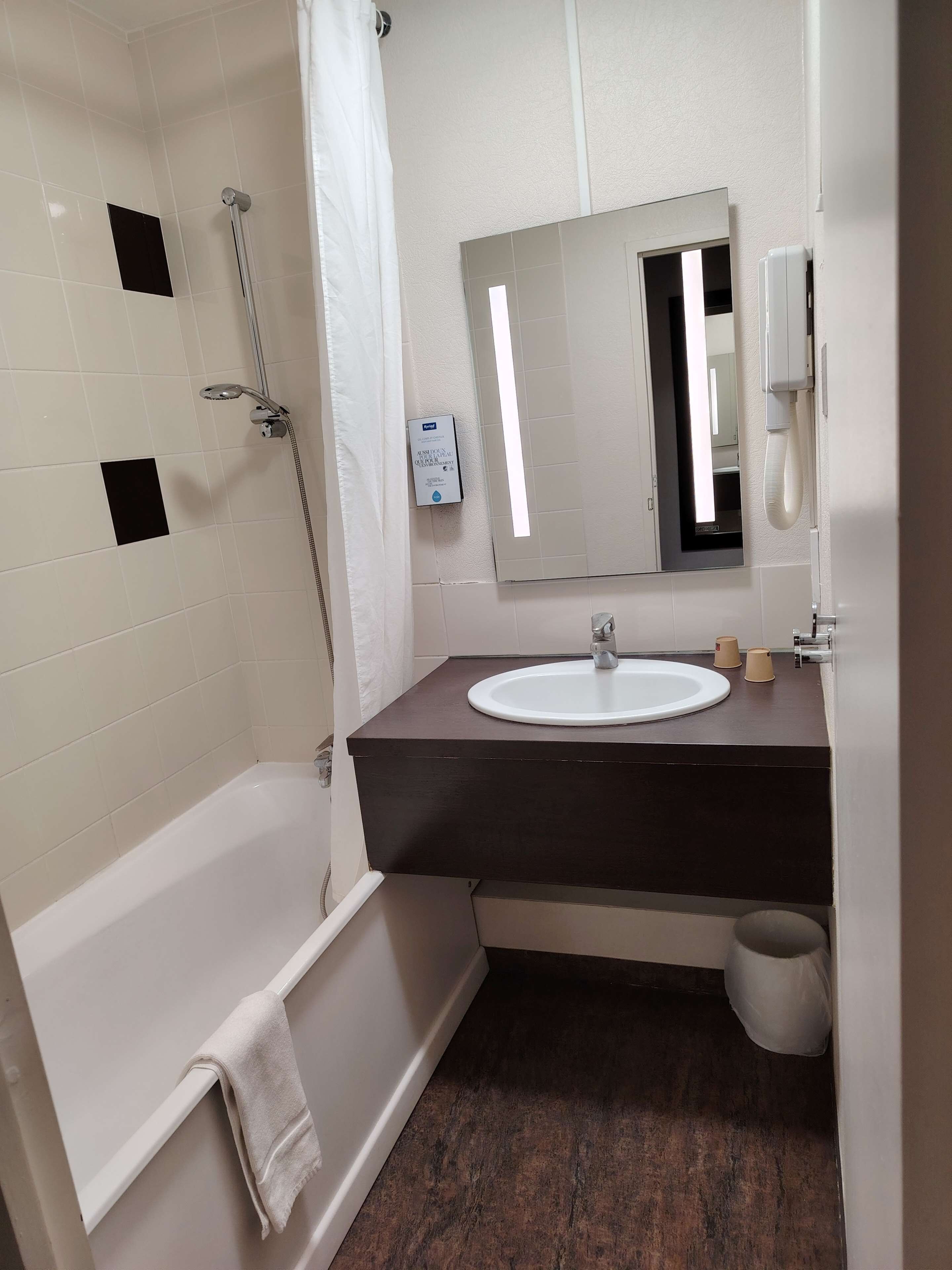 A bathroom with a bathtub, a sink, a mirror, and a shower.