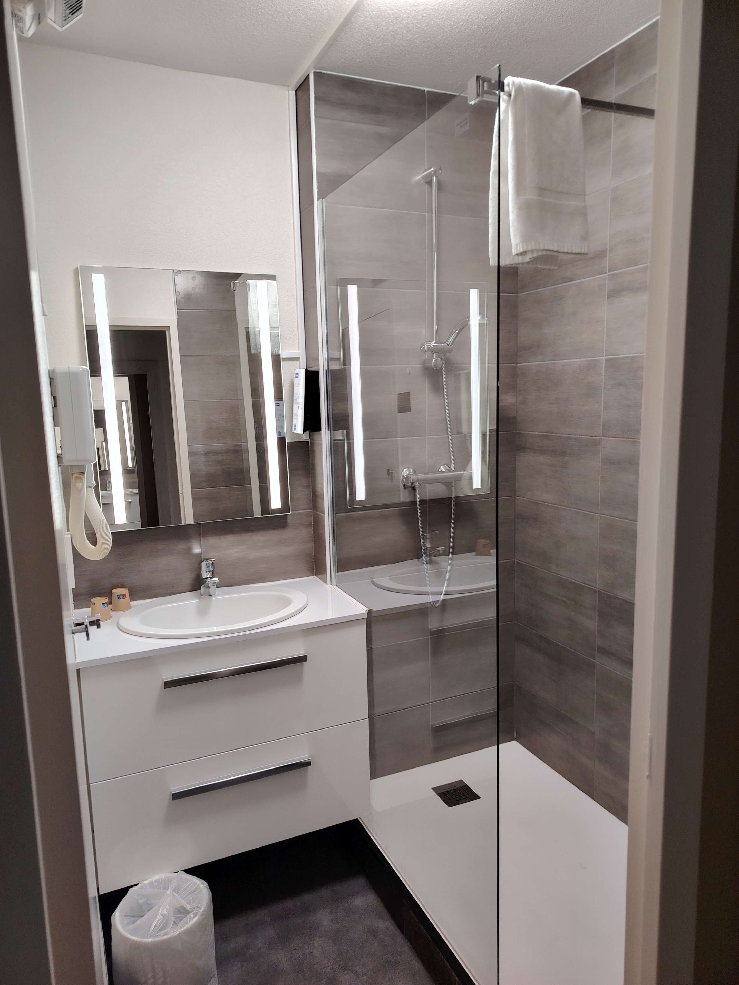 Une salle de bain moderne avec deux lavabos, une douche en verre et un miroir.