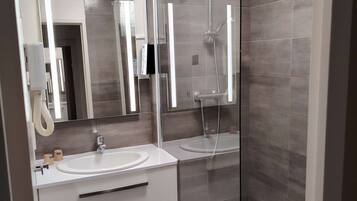 Une salle de bain moderne avec deux lavabos, une douche en verre et un miroir.