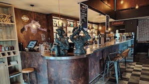 A bar area with a copper counter, stools, and a variety of bottles and glasses. - Kyriad Laon (Laon)