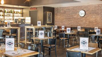 A restaurant interior with tables, chairs, a bar area, and a brick wall.