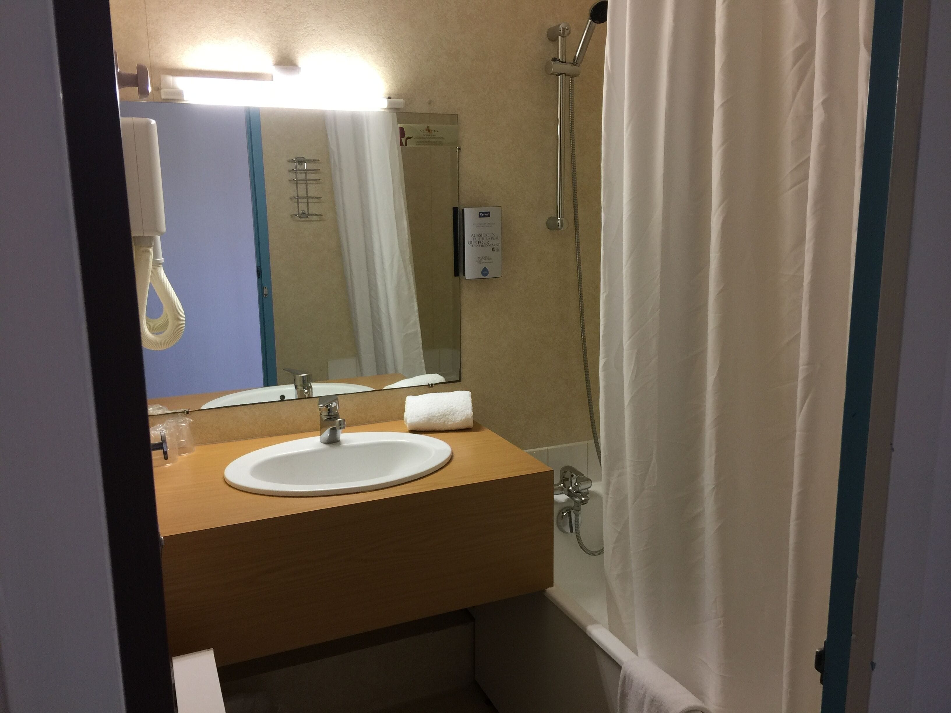 Un bagno con lavandino, specchio, doccia e portasciugamani.