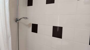 Een badkamer met witte betegelde wanden, een douche en een bad.
