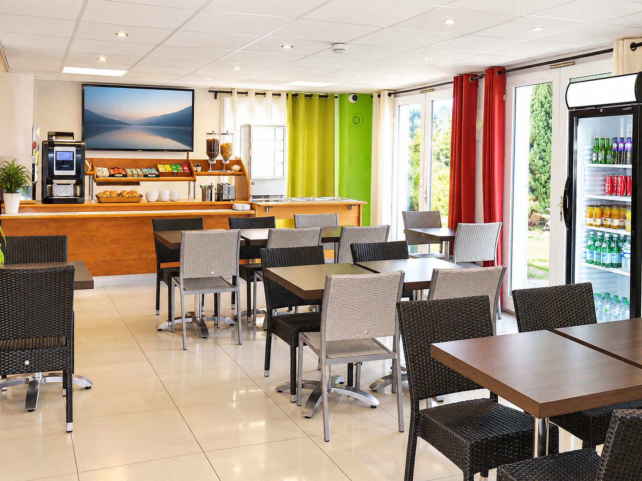 A hotel dining area with a bar, seating, and a refrigerator stocked with beverages.