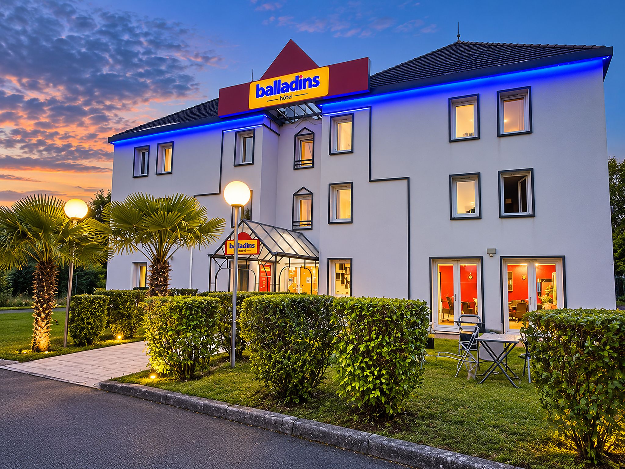 Un hotel dal design moderno, con un cartello ben visibile, numerose finestre e un ingresso luminoso.