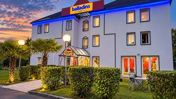 Un hotel dal design moderno, con un cartello ben visibile, numerose finestre e un ingresso luminoso.