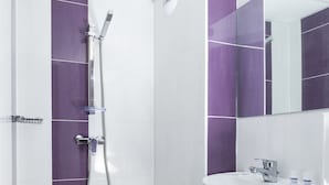 A modern bathroom with white and purple tiles, a shower, and a sink with a mirror above it. - Initial by Balladins St Quentin/Gauchy (Gauchy)