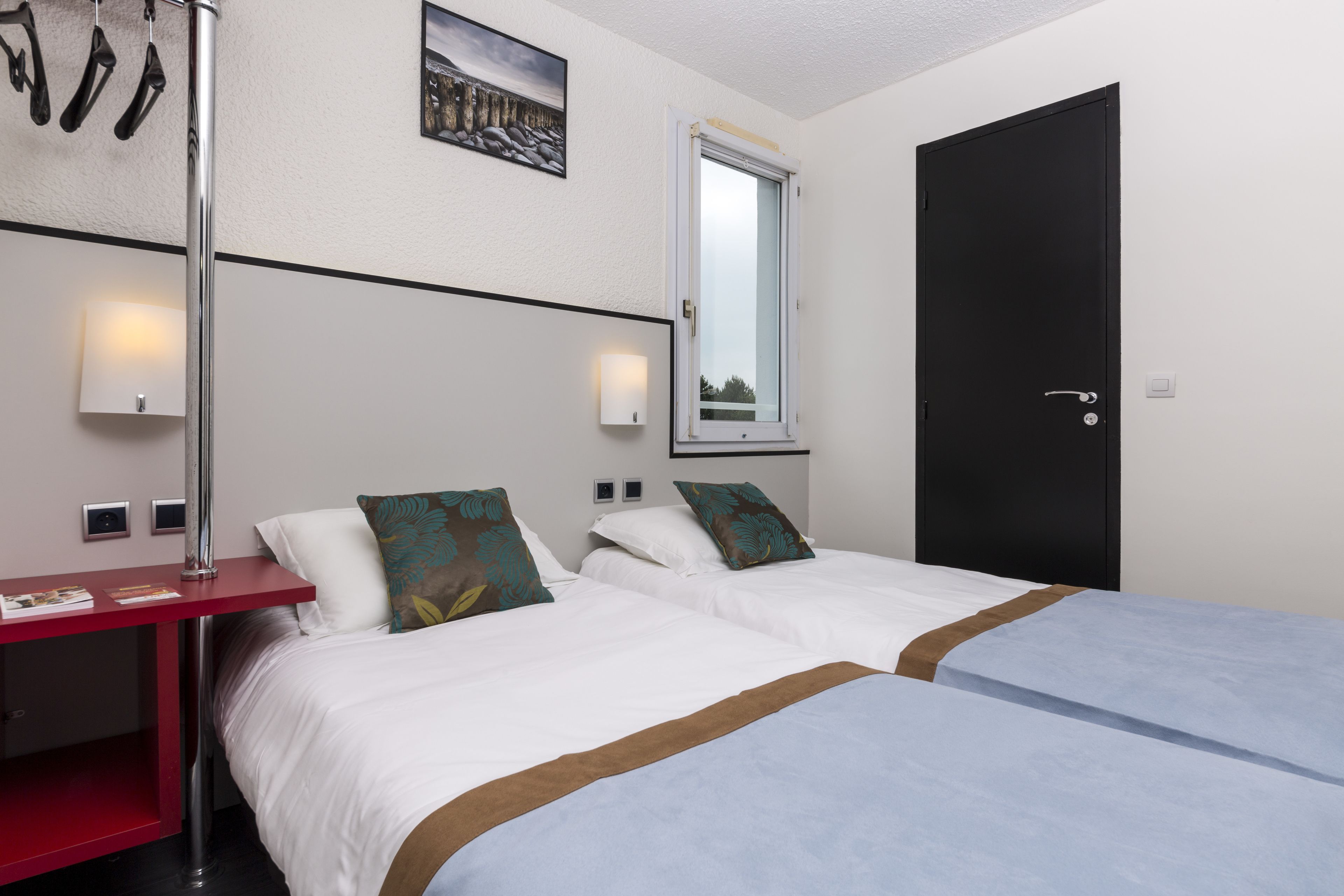 Une chambre d’hôtel avec deux lits, un bureau, un miroir et une porte.