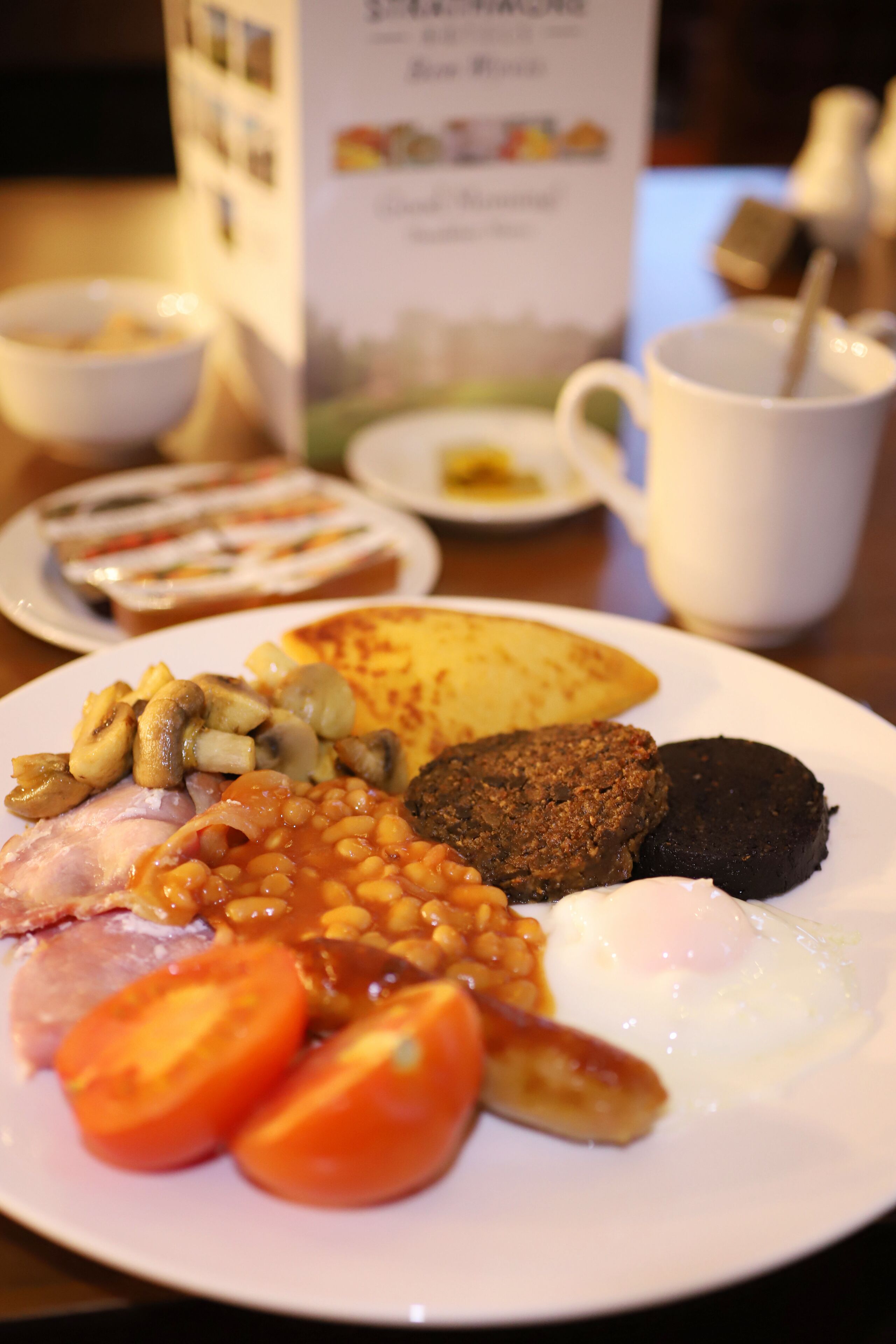A plate of breakfast food including eggs, tomatoes, beans, and sausages.