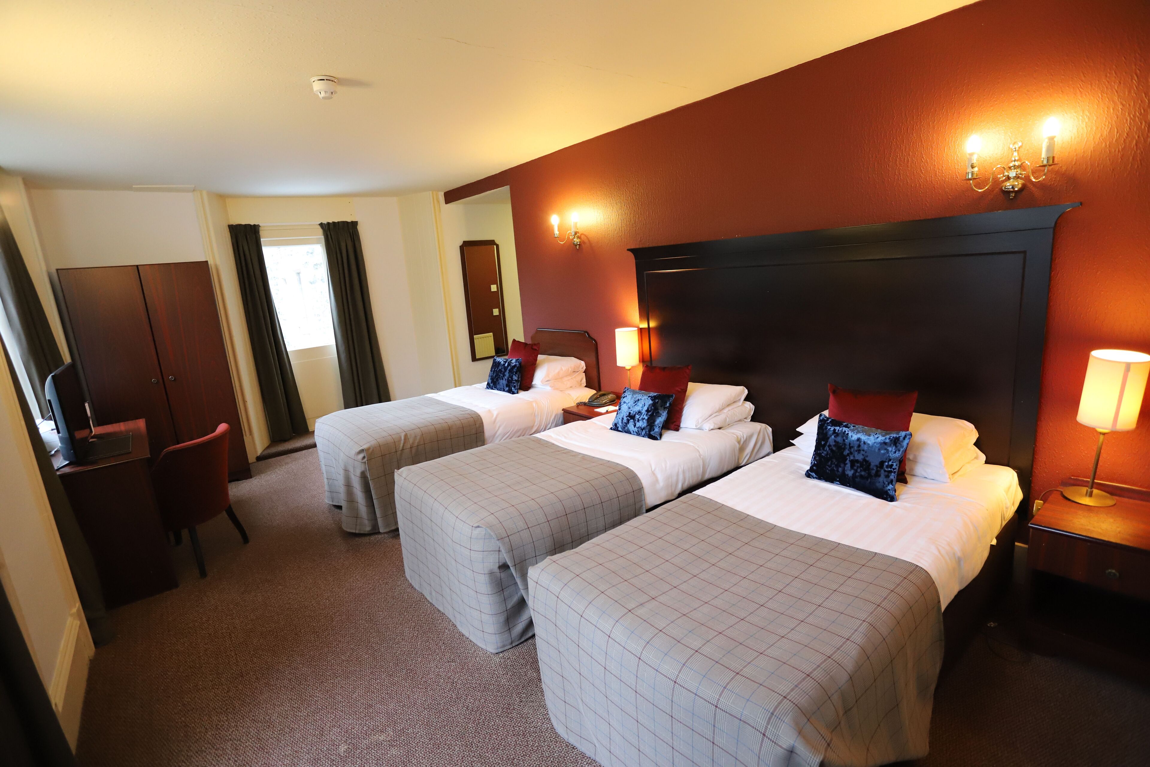 Habitación de hotel con dos camas, un escritorio y un armario.