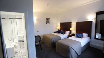 A hotel room with two beds, a bathroom, and a mirror.