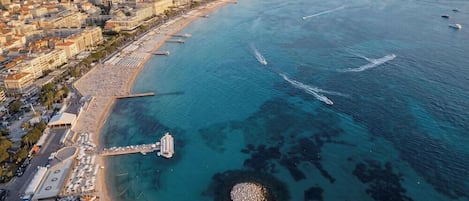 Luftaufnahme einer Küstenstadt mit Strand, einer Mole und einem Yachthafen.