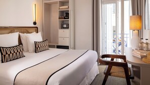 A hotel room with a large bed, a wardrobe, a desk with a lamp, and a view of the outside. - Crisol Belle Epoque (Cannes)