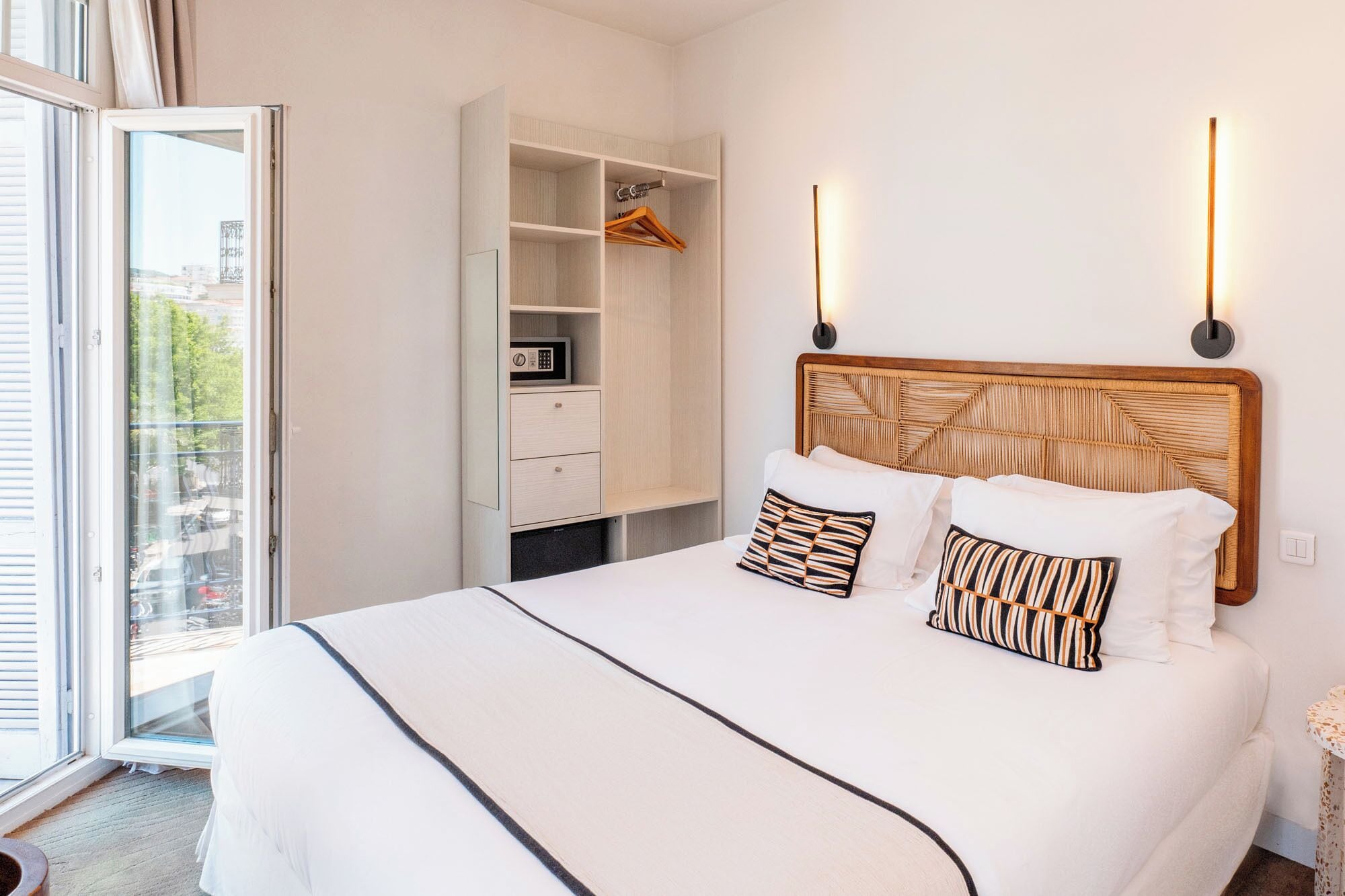Habitación de hotel con cama, armario, microondas y vistas por la ventana.