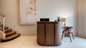 A reception area with a large abstract painting, a reception desk, a chair, and a staircase. - Crisol Belle Epoque (Cannes)
