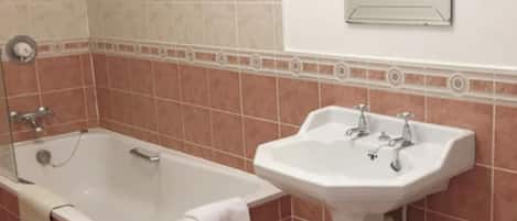 Un baño con bañera, lavabo y espejo en la pared.