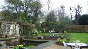 A garden with a pond, potted plants, and outdoor furniture. - Chapel House Restaurant with Rooms (Atherstone)